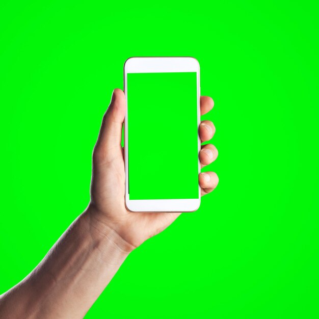 Menselijke hand toont mobiele smartphone met groen scherm