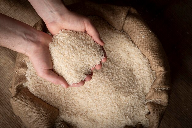 Menselijke handen die handvol rijst over jutezak houden