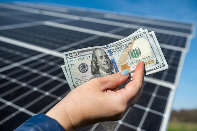 Menselijke handen met een grote hoeveelheid dollars voor zonnepanelen Het concept van energiebesparing