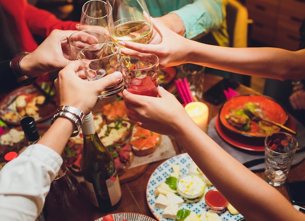 Menselijke handen met glazen rode wijn klinken ze over de bediende tafel