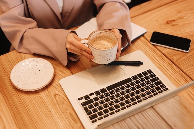 Foto menselijke handen typen op een laptop die op een houten tafel desktop staat met een koffiekop
