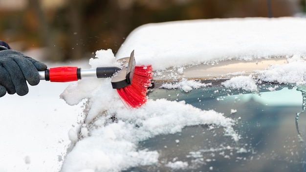 Menselijke handreinigende auto van sneeuw in de winterdag