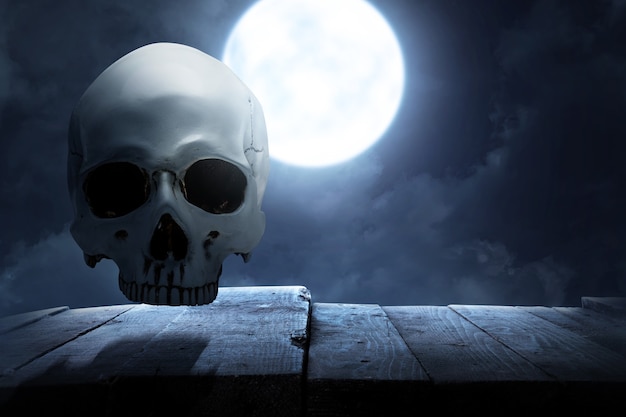 Menselijke schedel op houten tafel met de achtergrond van de nachtscène