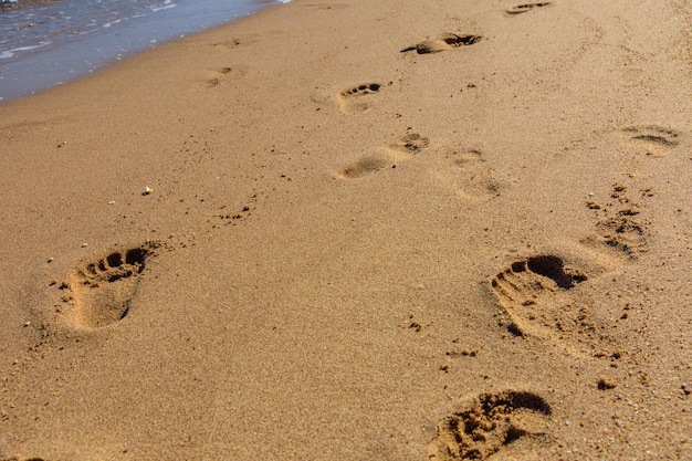 Menselijke voetafdrukken op het zandstrand Zomervakantie concept