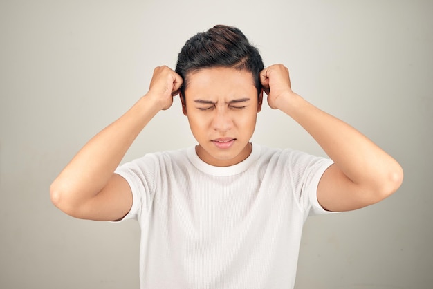Mensen benadrukken spanning en migraineconcept Verstoorde ongelukkige jongeman die in zijn hoofd knijpt met handen die aan hoofdpijn lijden
