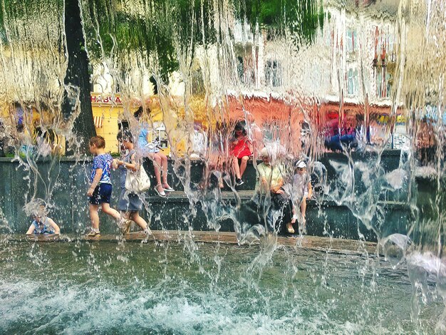 Foto mensen bij de fontein gezien door het vallende water