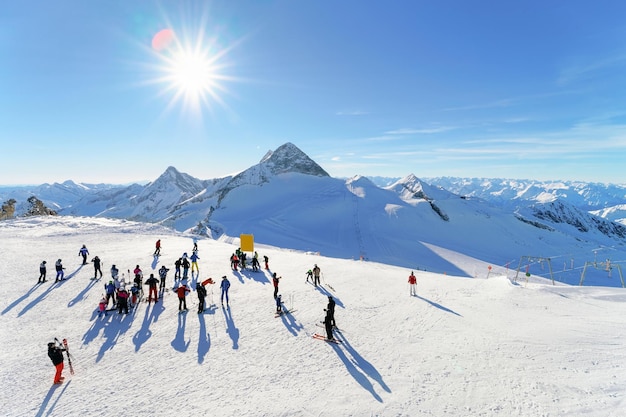Mensen bij Hintertux-gletsjerskitoevlucht in Zillertal in Tirol in Oostenrijk in de winter in Alpen. Alpine bergen met sneeuw. Afdaling leuk. Familie vakantie. Blauwe lucht en witte hellingen.