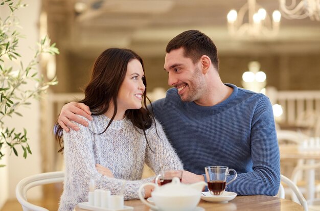 mensen, communicatie en dating concept - gelukkige paar thee drinken en knuffelen in café of restaurant