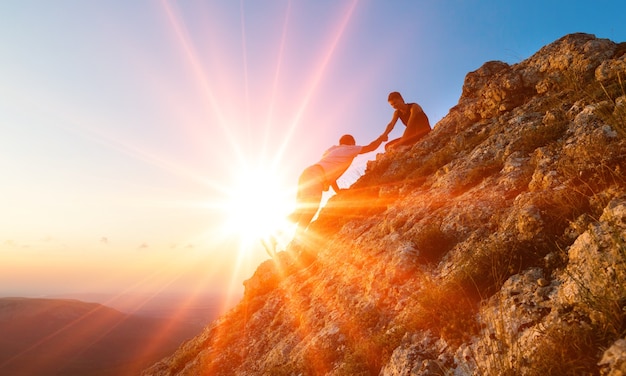 Mensen die elkaar helpen wandelen op de berg