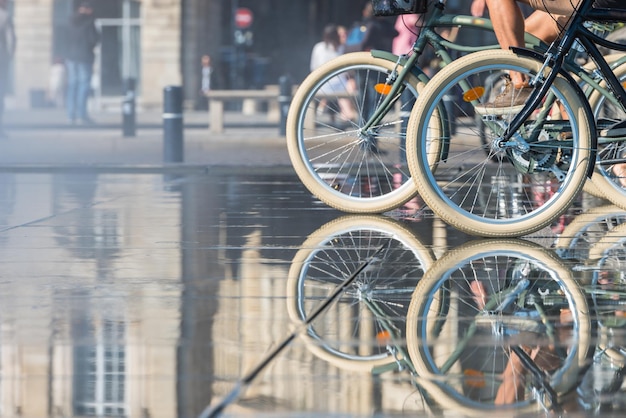 Foto mensen die fietsen berijden in de spiegelfontein voor place de la bourse in bordeaux, frankrijk