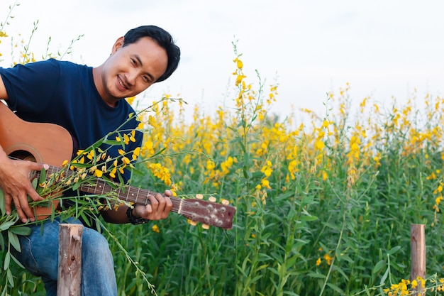 Mensen die gitaar in Mooie Sunhemp-bloem in tuin spelen