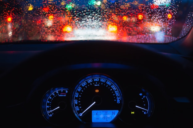 Mensen die moderne auto in nacht met licht en daling van water drijven bokeh bij regenende dag