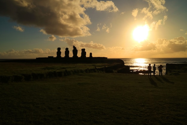 Mensen die op zonsondergang over Vreedzame oceaan in Ahu Tahai met Moai-standbeelden, Pasen-Eiland, Chili letten