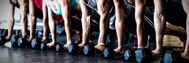 Mensen die push-ups doen met halters in de sportschool