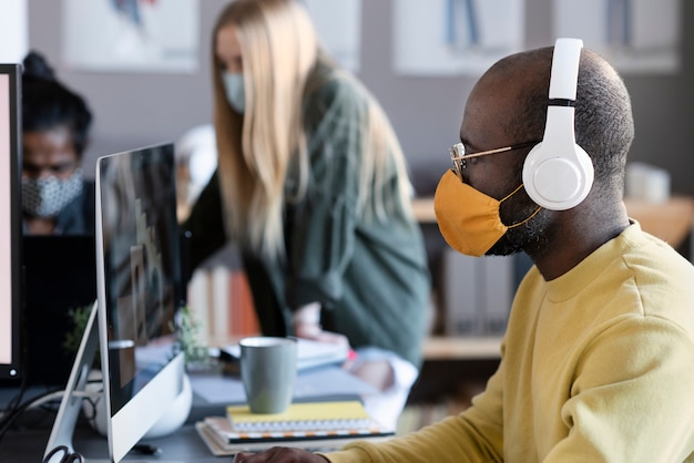 Mensen die samenwerken in een animatiestudio terwijl ze medische maskers dragen