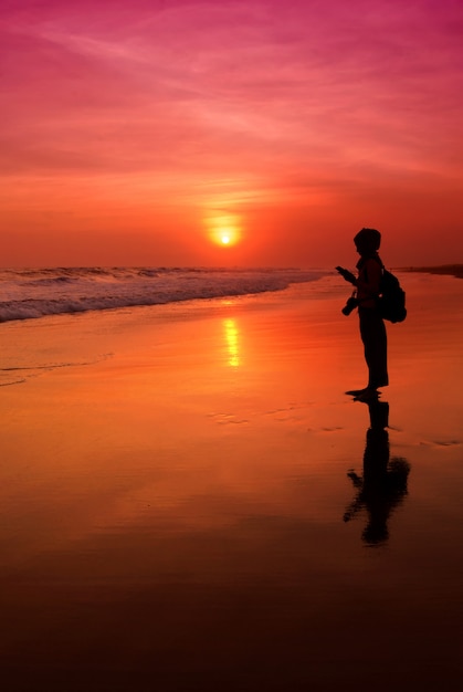 Mensen die tijdens zonsondergang bij Parangtritis-Strand, Yogyakarta texting.