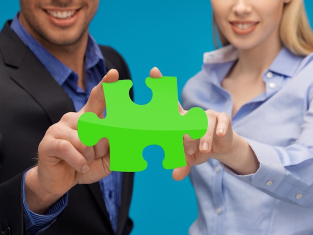 Mensen, ecologie, strategie en bedrijfsconcept - man en vrouwenhanden met groene puzzel