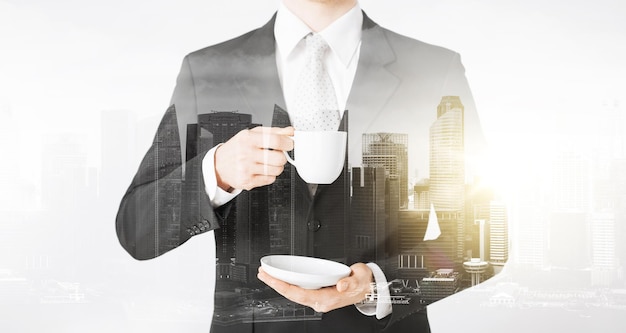 mensen en bedrijfsconcept - close-up van zakenman die koffie drinkt uit de beker over de stad met dubbele belichting