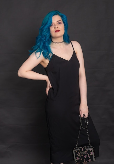 Mensen en mode concept - vrouw gekleed in zwarte jurk en blauw haar poseren op zwarte achtergrond.