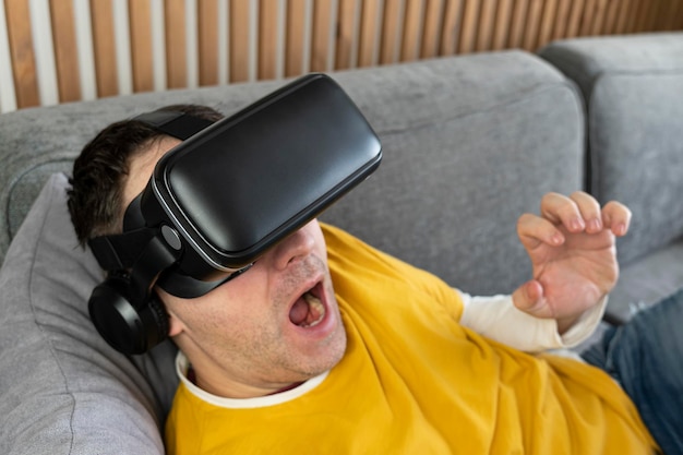 Mensen en technologie metaverse concept man kijken naar een video in virtual reality bril liggen op de bank thuis 360 graden video bekijken