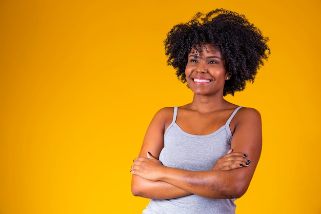 Mensen etniciteit en portret concept gelukkig lachende vrouw in shirt met gekruiste armen over gele achtergrond