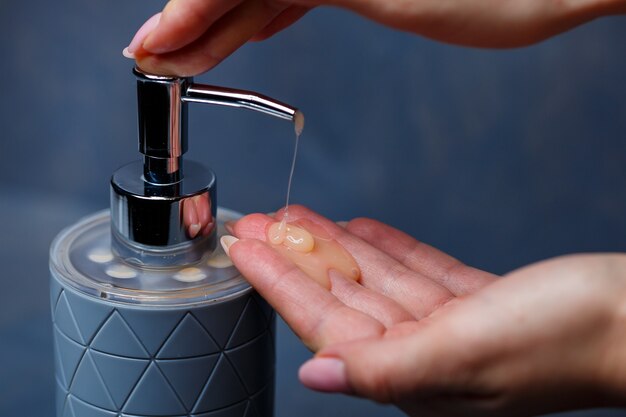 Mensen gebruiken de zeepdispenser met een metalen dop van grijs op een grijze tafel