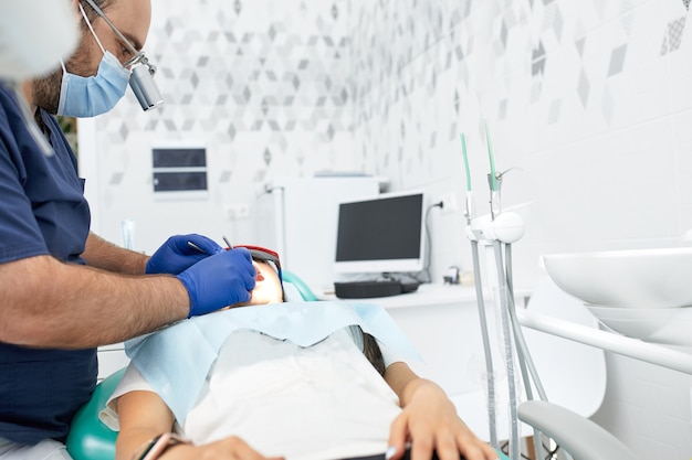 Mensen geneeskunde stomatologie en gezondheidszorg concept - gelukkige mannelijke tandarts met vrouwelijke patiënt op het kantoor van de tandheelkundige kliniek.