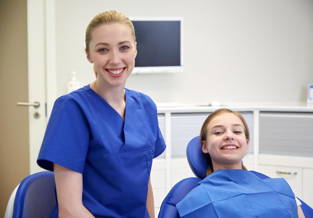 mensen, geneeskunde, stomatologie en gezondheidszorgconcept - gelukkige vrouwelijke tandarts met geduldig meisje op het kantoor van de tandheelkundige kliniek