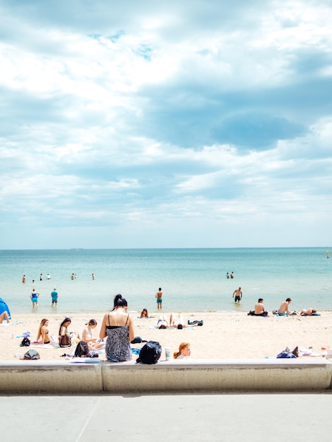 Foto mensen genieten van het strand en de zee tegen een bewolkte lucht.