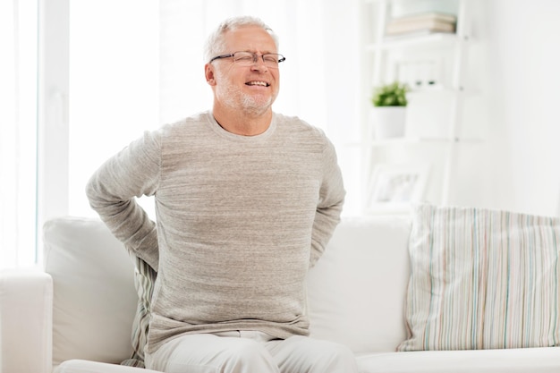 mensen, gezondheidszorg en probleemconcept - ongelukkige senior man die thuis pijn heeft in de rug of teugels