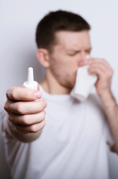 Mensen, gezondheidszorg, rhinitis, koude en allergie concept - zieke man met papier en druppels voor de neus