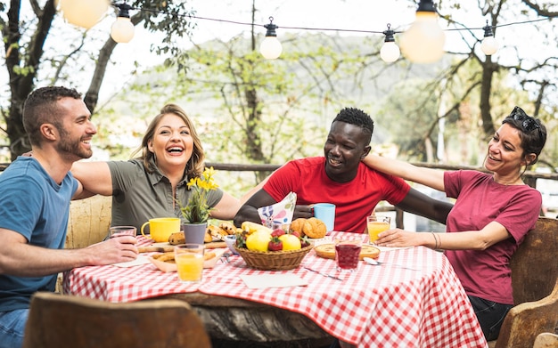 Mensen groep drinken koffie en vruchtensap bij picknick ontbijt vrienden praten en plezier samen thuis tijdens brunch lifestyle concept met gelukkige mannen en vrouwen op vakantie