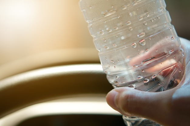 Mensen houden waterfles en stuurwiel voor verfrissend drankje en auto rijden