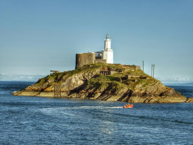 Foto mensen in een motorboot bij mumbles vuurtoren in swansea bay tegen de lucht