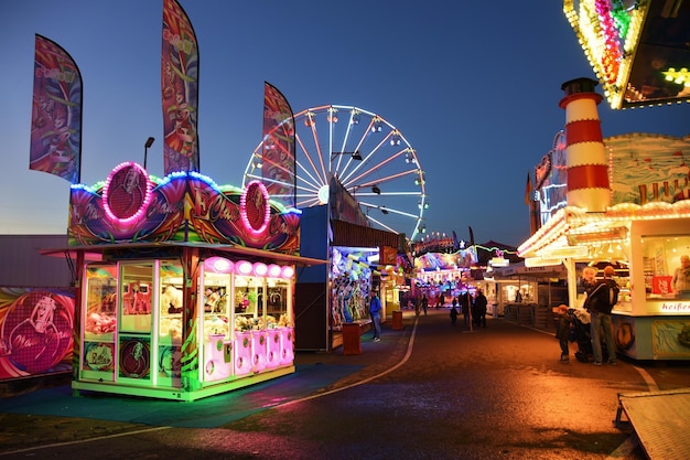 Mensen in een verlicht pretpark tegen de hemel's nachts