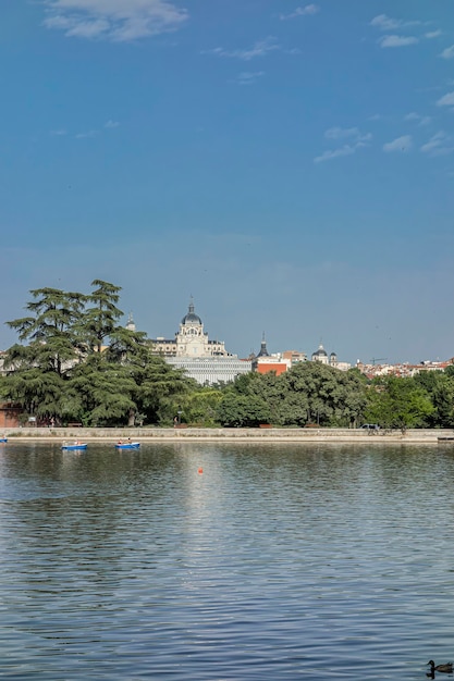 Mensen in roeiboten op het meer van het landhuis van Madrid op een zomerdag en met uitzicht op de Almudena-kathedraal