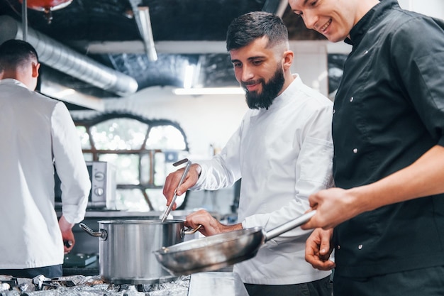 Mensen in wit uniform koken samen eten in de keuken Drukke dag op het werk