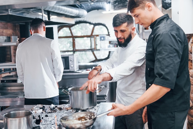 Mensen in wit uniform koken samen eten in de keuken Drukke dag op het werk