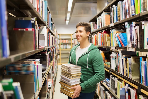 mensen, kennis, onderwijs, literatuur en schoolconcept - gelukkige student of jonge man met boek in bibliotheek