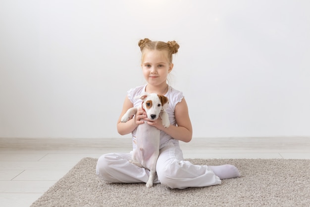 Mensen, kinderen en huisdierenconcept - klein kindmeisje dat op de vloer ligt met schattige puppy Jack Russell Terrier