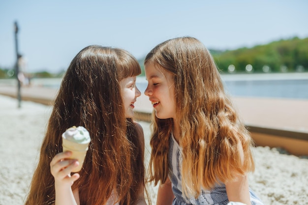 Mensen kinderen vrienden en vriendschap concept vrolijke kleine meisjes die ijs eten op het strand