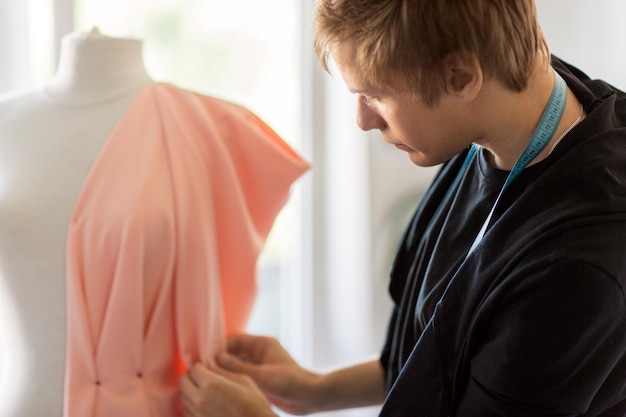 Foto mensen kleding en tailoring concept close-up van modeontwerper met dummy doek en pinnen maken nieuwe jurk in de studio