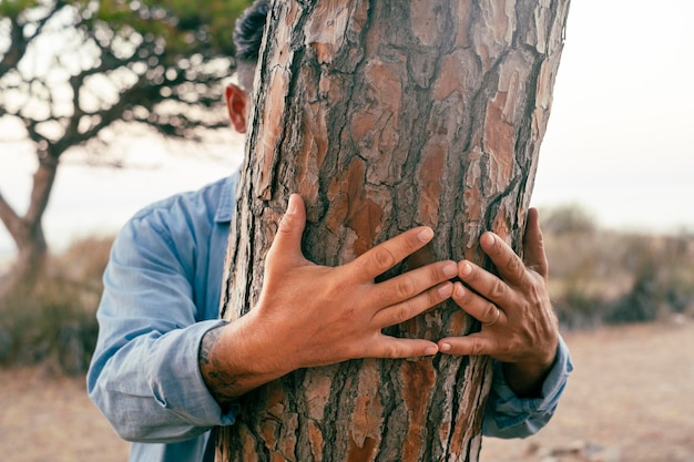 Mensen knuffelen boom Natuur milieu klimaatverandering en bescherming leven Verborgen mannelijke omhelzing een stam verlijmen in het park Close-up van handen op het hout De natuur aanraken in vrijetijdsbesteding buitenshuis