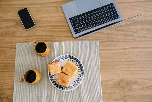 Mensen laptop telefoon en ontbijt op een houten tafel