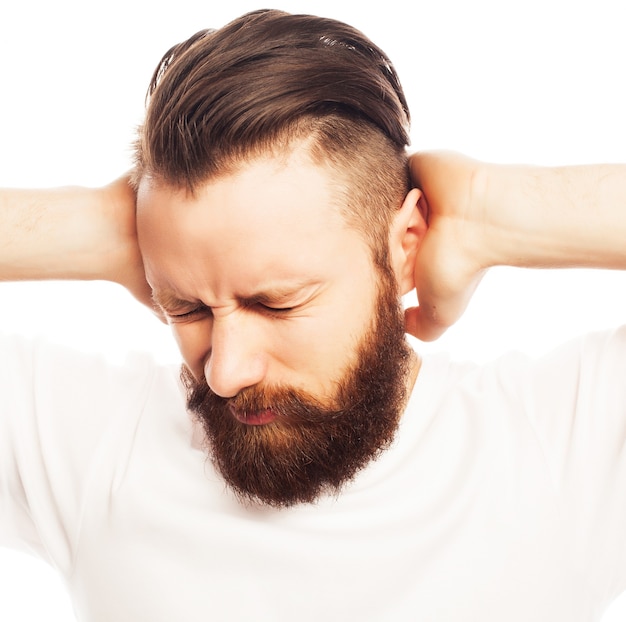 Mensen, levensstijl en emotioneel concept - bebaarde man die zijn oren bedekt door handen over witte achtergrond