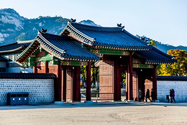 Mensen lopen bij de ingang van gyeongbokgung tegen een heldere lucht.