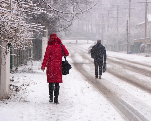 Mensen lopen in de vroege ochtend tijdens een sneeuwval door een besneeuwde straat. Stadsgezicht