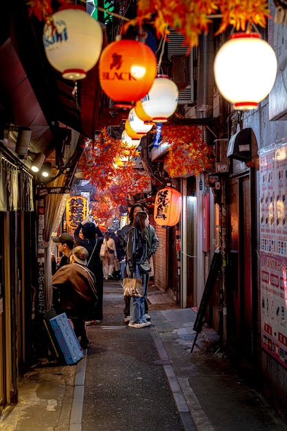 Mensen lopen in een smalle straat versierd met papieren lantaarns in Japan