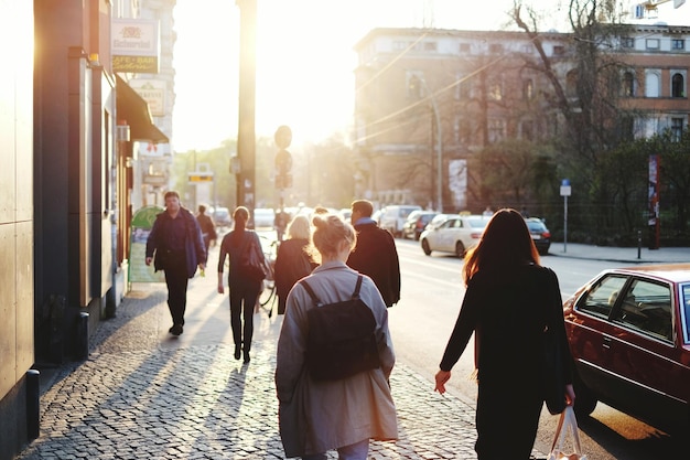 Mensen lopen op de stoep in de stad tegen de heldere zon.