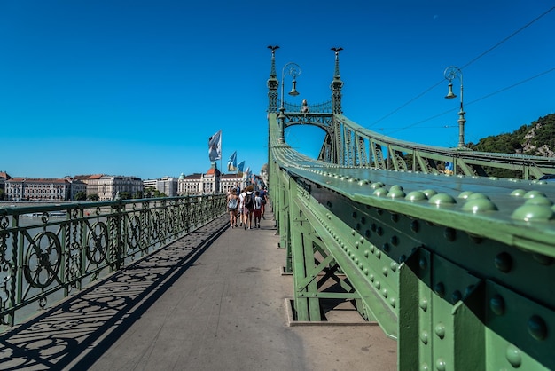 Mensen lopen op een hangbrug tegen de blauwe hemel.